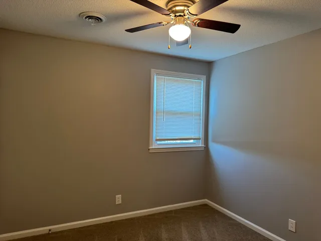 an empty room with a window and a fan