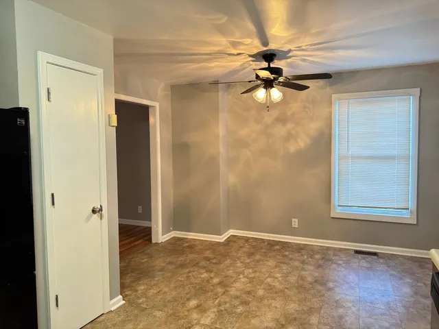 an empty room with windows and fan