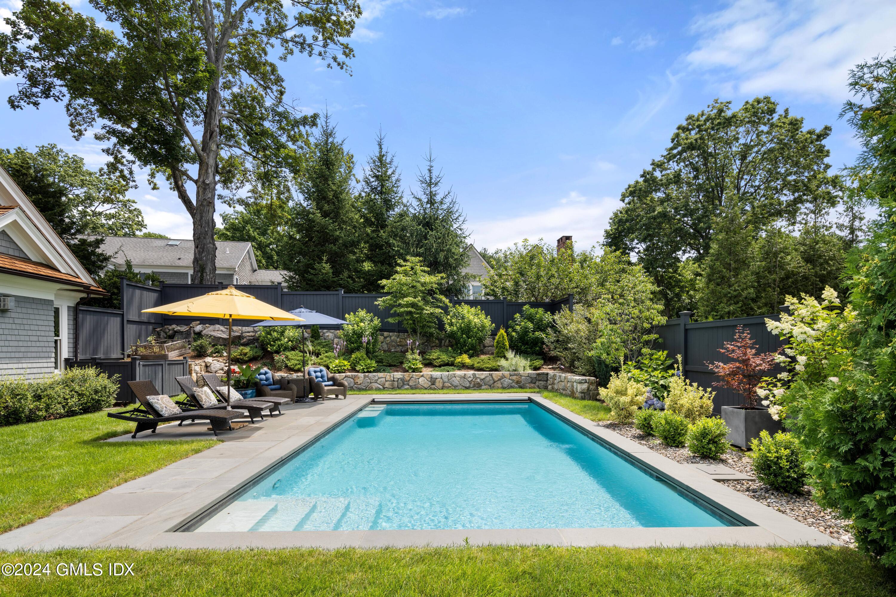 106 Lockwood Road Riverside, CT 06878 - Photo 31 of 38 a view of a swimming pool with lawn chairs under an umbrella