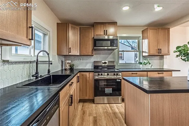 a kitchen with stainless steel appliances granite countertop a sink a stove and a microwave