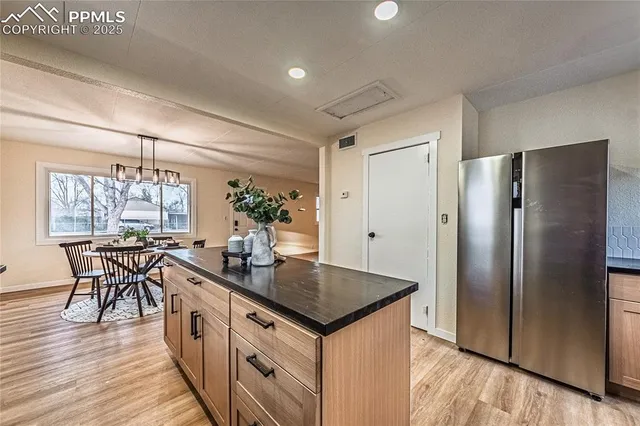 a kitchen with stainless steel appliances granite countertop a table chairs stove and refrigerator