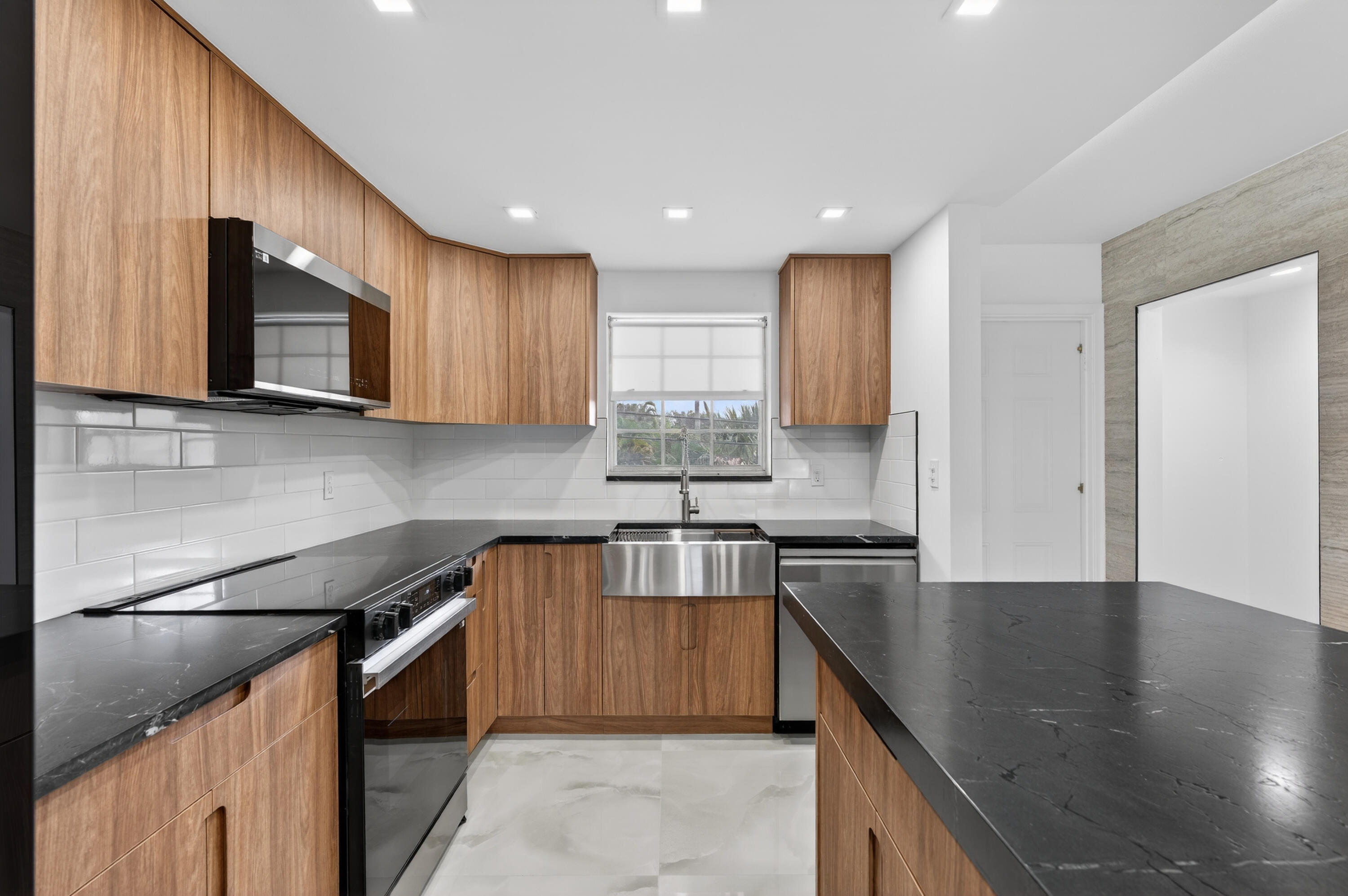 2134 Northeast 36th Street, Unit 82 Lighthouse Point, FL 33064 - Photo 5 of 38 a kitchen with stainless steel appliances granite countertop sink stove microwave and cabinets