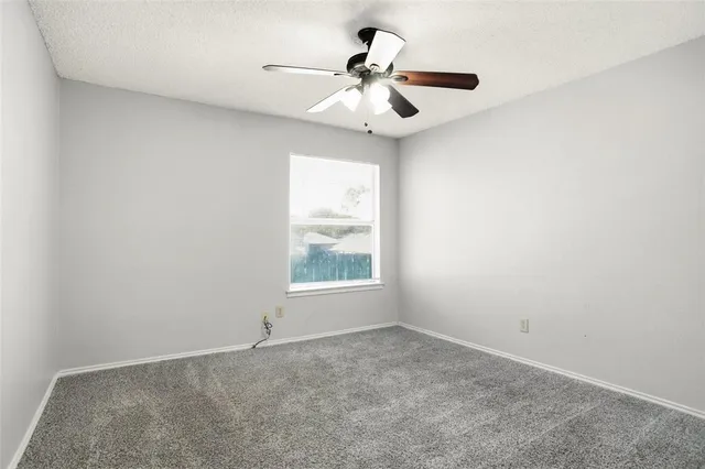 an empty room with a chandelier fan and windows