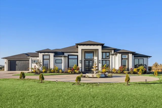 a view of a white house with a big yard and couches chairs and large trees