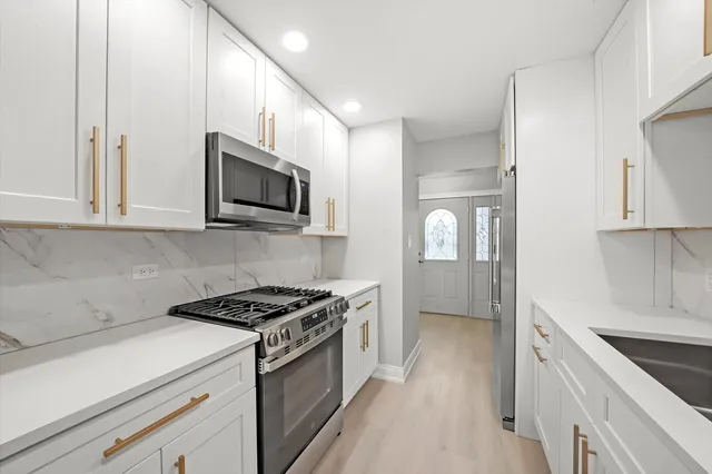 a kitchen with stainless steel appliances granite countertop white cabinets a microwave a sink and dishwasher