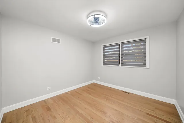 an empty room with wooden floor and window