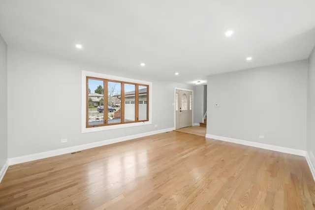 an empty room with wooden floor and window