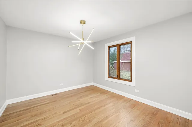 an empty room with wooden floor closet and windows