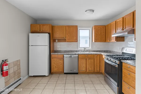 a kitchen with granite countertop a refrigerator and a stove top oven