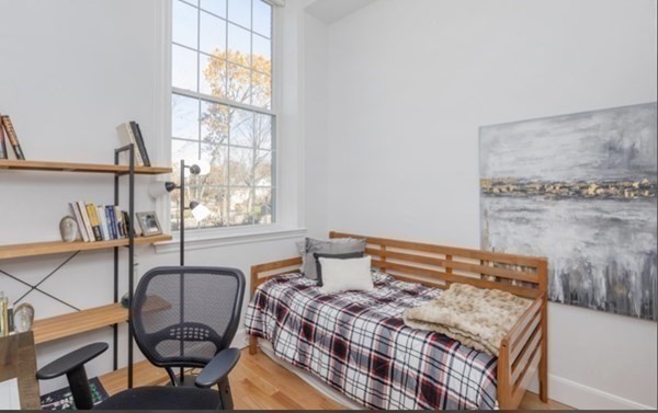 52 Sanborn Street, Unit 102 Reading, MA 01867 - Photo 19 of 28 a bedroom with a bed a table and chair with the floor to ceiling window
