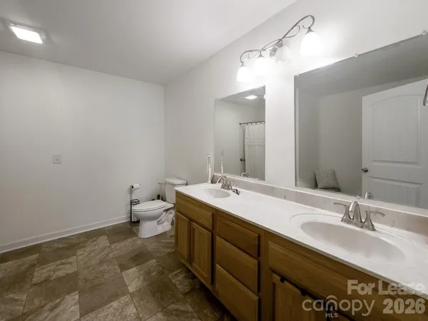a bathroom with a double vanity sink and mirror with toilet