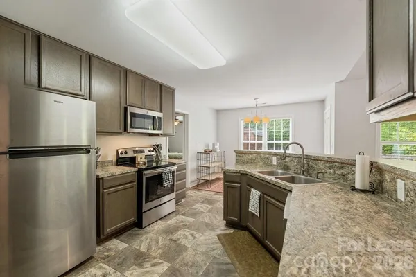 a kitchen with stainless steel appliances granite countertop a stove a sink dishwasher a refrigerator and a microwave