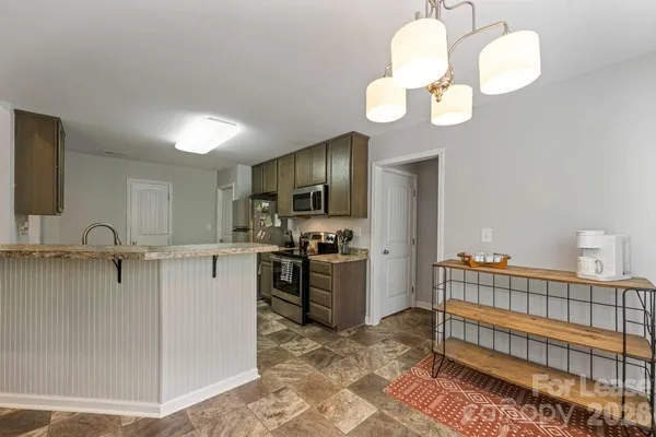 a kitchen with stainless steel appliances granite countertop a sink dishwasher a stove and a refrigerator with wooden floor