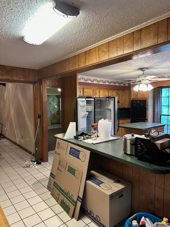 408 Myra Street Mansfield, LA 71052 - Photo 9 of 16 Kitchen featuring ceiling fan, stainless steel fridge, a textured ceiling, wooden walls, and oven
