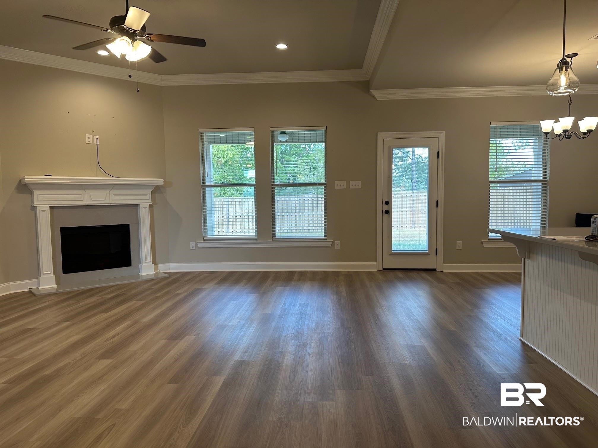 1009 Ruisseau Drive Foley, AL 36535 - Photo 13 of 55 Unfurnished living room with crown molding, dark hardwood / wood-style floors, and ceiling fan with notable chandelier