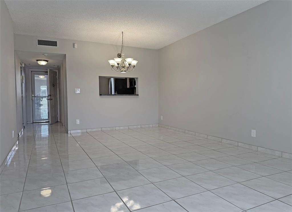 3001 Holiday Springs Boulevard, Unit 102 Margate, FL 33063 - Photo 4 of 18 an empty room with chandelier and glass door