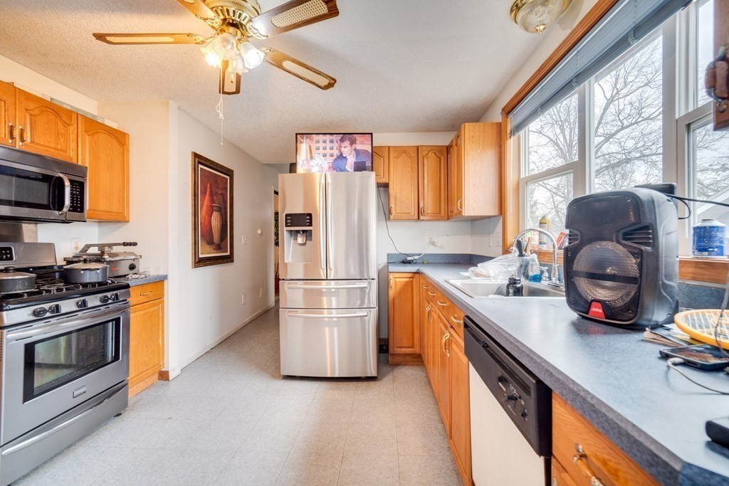 104 Phoenix Terrace Springfield, MA 01104 - Photo 5 of 8 a kitchen with stainless steel appliances granite countertop a refrigerator a stove a sink dishwasher a dining table and chairs with wooden floor