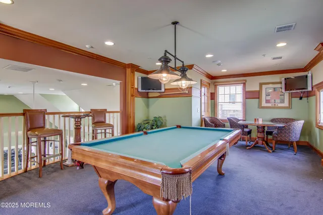 a room with furniture pool table wooden floor and windows