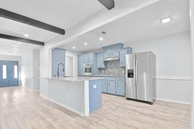 a kitchen with stainless steel appliances granite countertop a refrigerator and a stove top oven