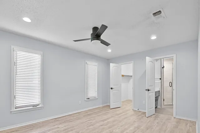 a view of empty room with wooden floor and ceiling fan