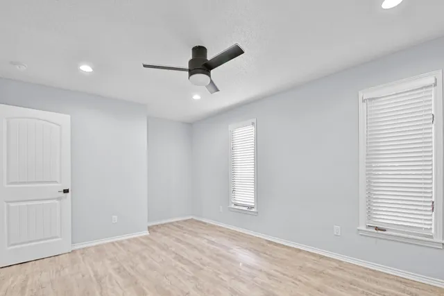 a view of empty room with wooden floor and fan