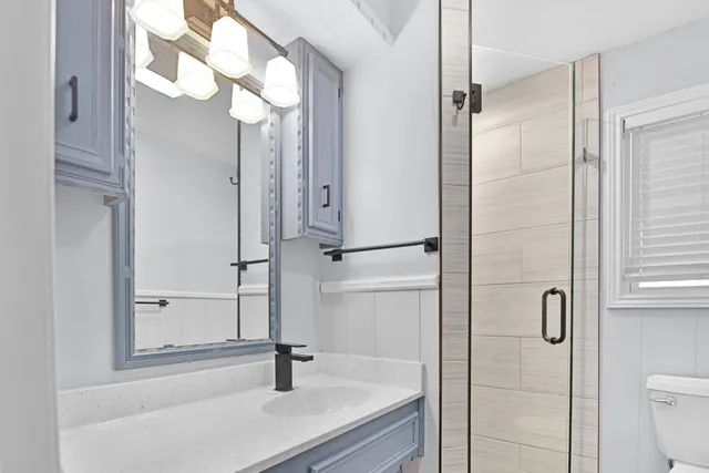 a bathroom with a sink a toilet and shower