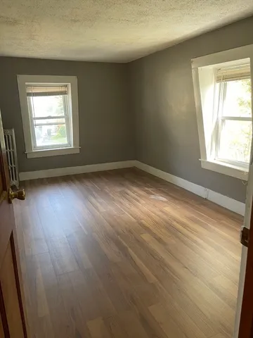 a view of empty room with wooden floor and window