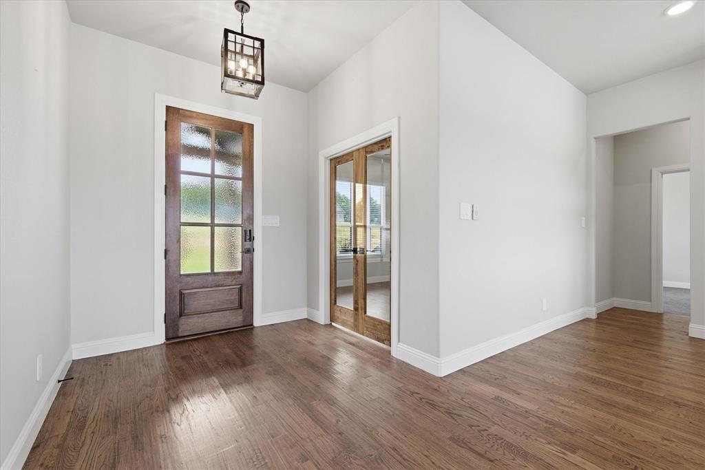 120 Grace Vw Road Weatherford, TX 76088 - Photo 7 of 40 Hardwood flooring extends throughout this entry space, featuring a dark wood front door with frosted glass panels and a complementary wood-frame double door with clear glass