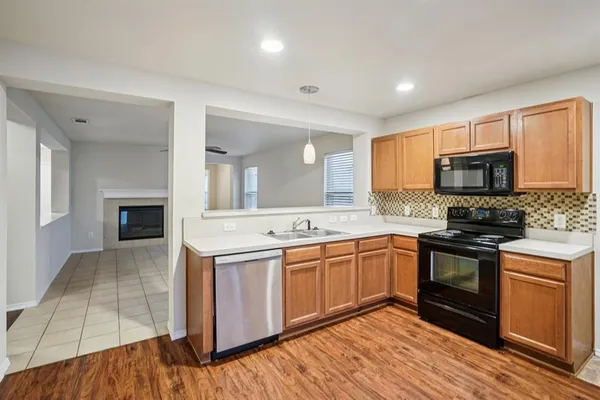 a kitchen with stainless steel appliances granite countertop a stove top oven a sink dishwasher and a refrigerator with wooden floor