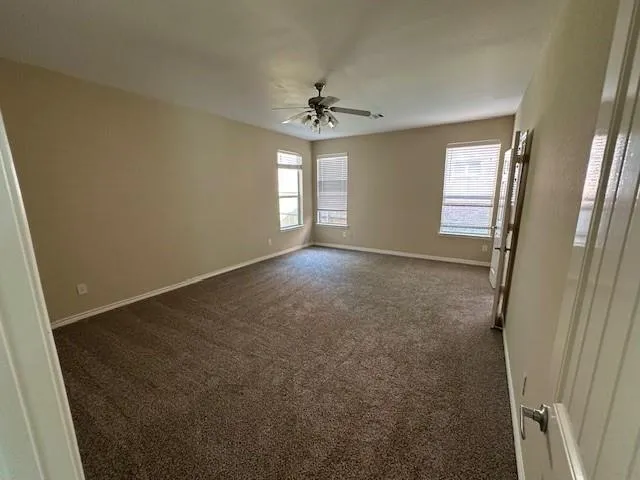 an empty room with windows and fan