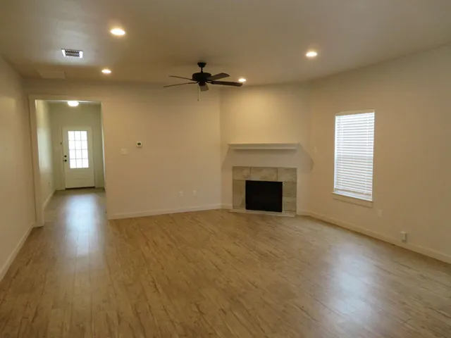 an empty room with wooden floor fireplace and windows