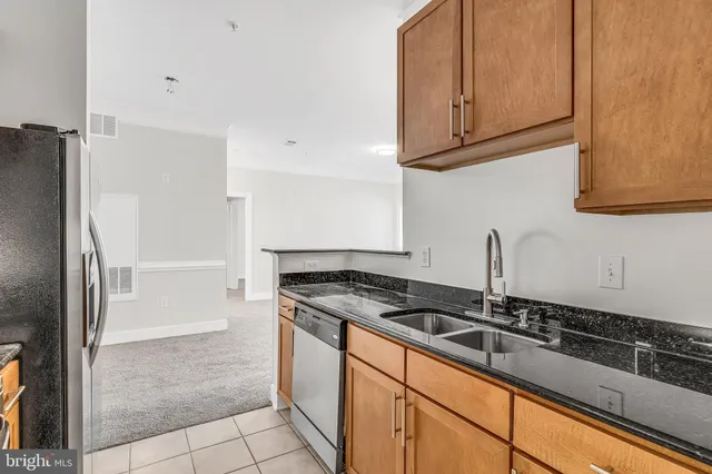 a kitchen with granite countertop a sink and a refrigerator