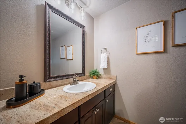 a bathroom with a granite countertop sink a mirror and vanity