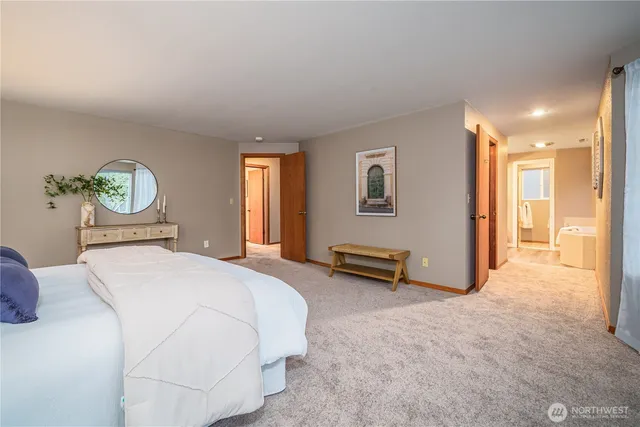 a spacious bedroom with a bed a table and painting on the wall