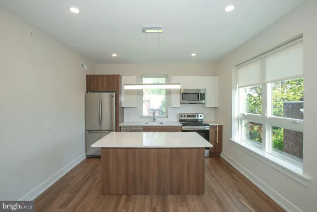 a large kitchen with stainless steel appliances a large counter top a stove a chimney a sink and a large window