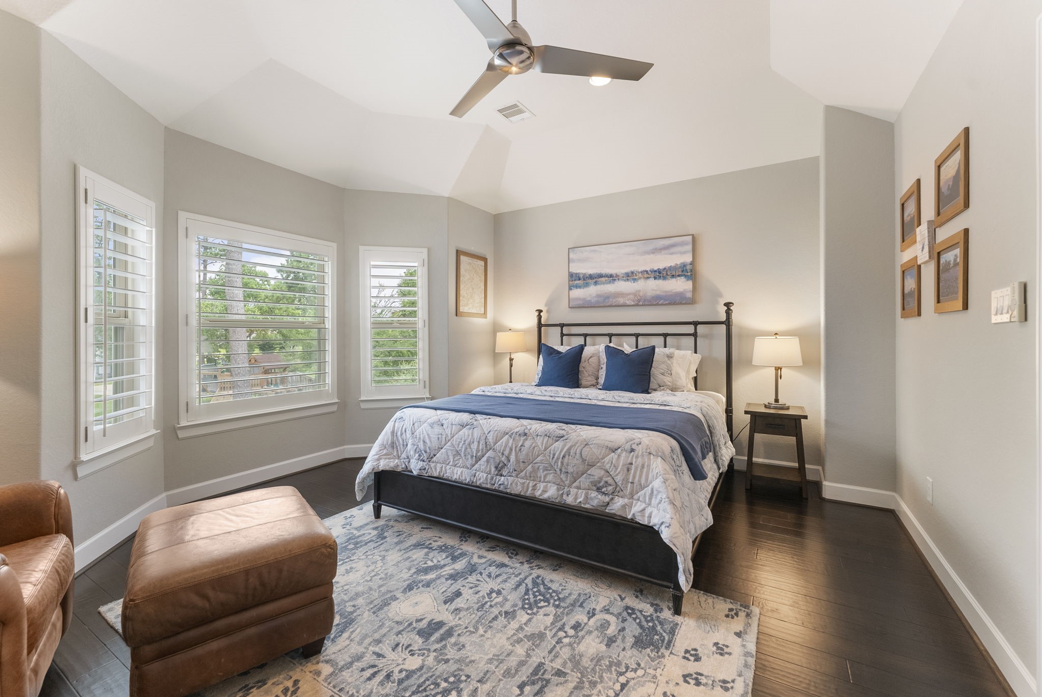 25607 Muirfield Bend Court Spring, TX 77389 - Photo 20 of 30 Spacious secondary bedroom featuring rich wood flooring, vaulted ceilings, plantation shutters, and oversized windows that fill the room with natural light. Thoughtfully designed with generous proportions and ample wall space, offering a comfortable and private retreat for family and guests.