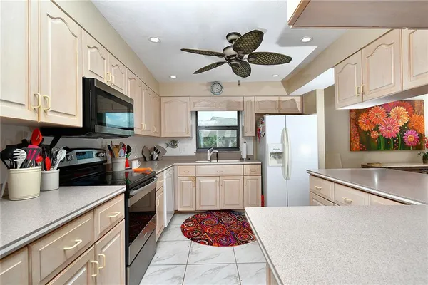 a kitchen with stainless steel appliances granite countertop a refrigerator a stove a microwave oven a sink dishwasher and white cabinets with wooden floor