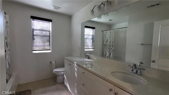 a bathroom with a granite countertop toilet a sink a mirror and a window