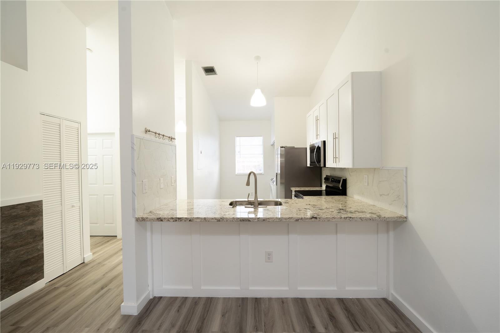 a view of kitchen with granite countertop cabinets and refrigerator