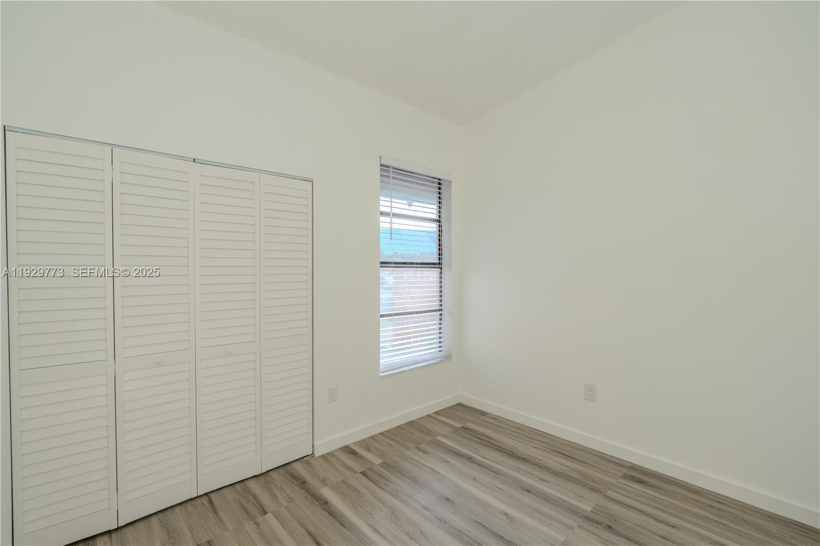 6725 Northwest 192nd Lane Hialeah, FL 33015 - Photo 14 of 29 an empty room with wooden floor and windows