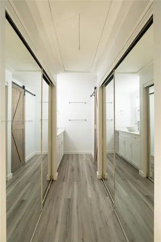 a view of a hallway with wooden floor and a bathroom