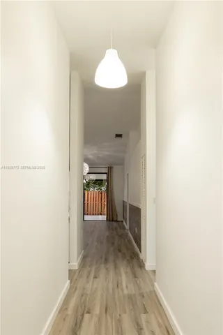 a view of a hallway with wooden floor and a bathroom