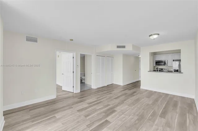 a view of an empty room with wooden floor and a window