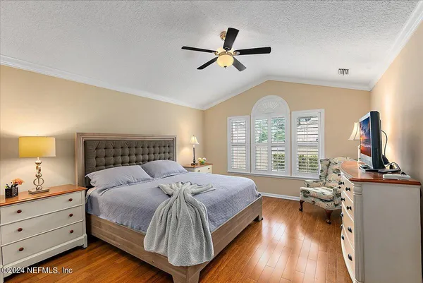 a bedroom with a bed and a flat tv screen on dresser