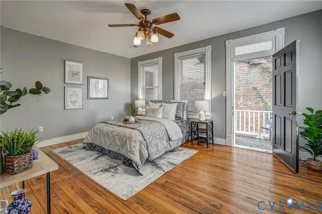 a view of an empty room with wooden floor and a ceiling fan