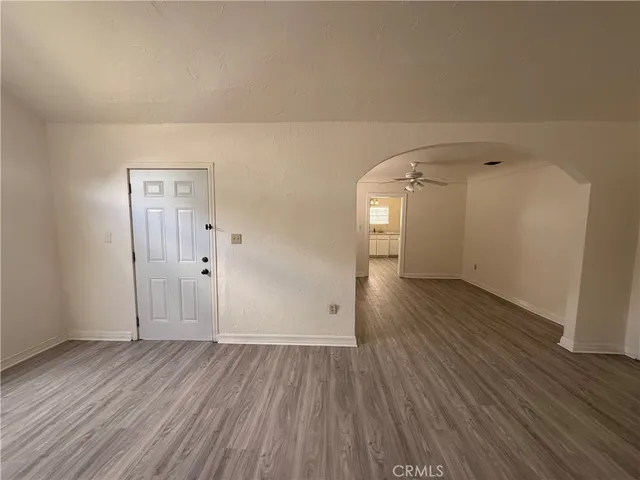 an empty room with wooden floor cabinet and windows
