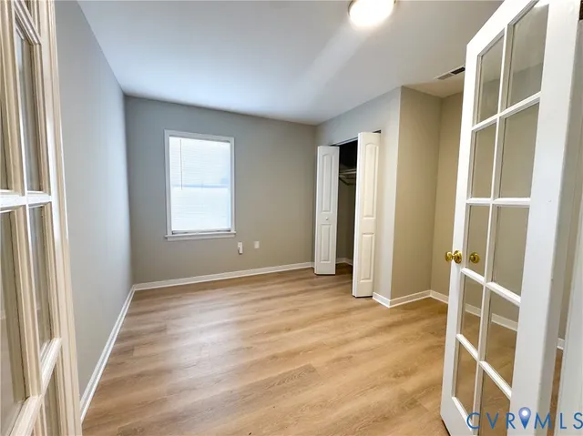 a view of an empty room with wooden floor and a window