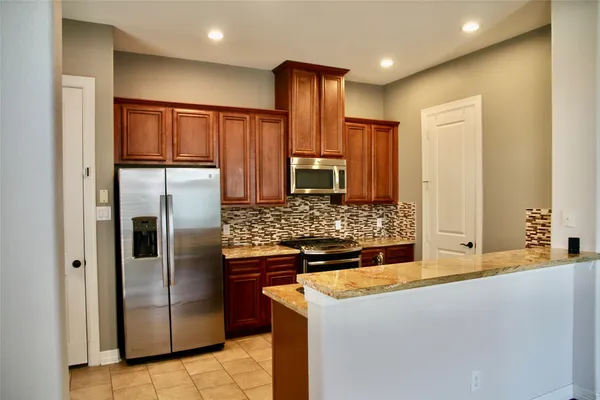 a kitchen with stainless steel appliances granite countertop a refrigerator and a stove
