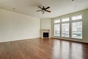 an empty room with wooden floor fan and windows