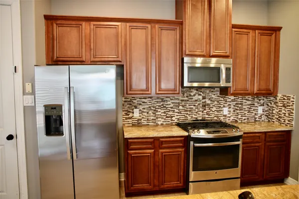 a kitchen with stainless steel appliances granite countertop a stove a refrigerator and a microwave